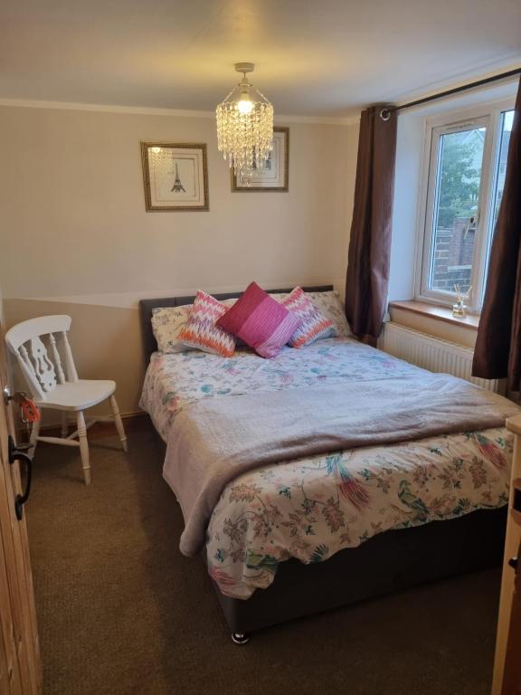 a bedroom with a bed and a chair and a chandelier at Mallard Cottage Guest House in Aylesford