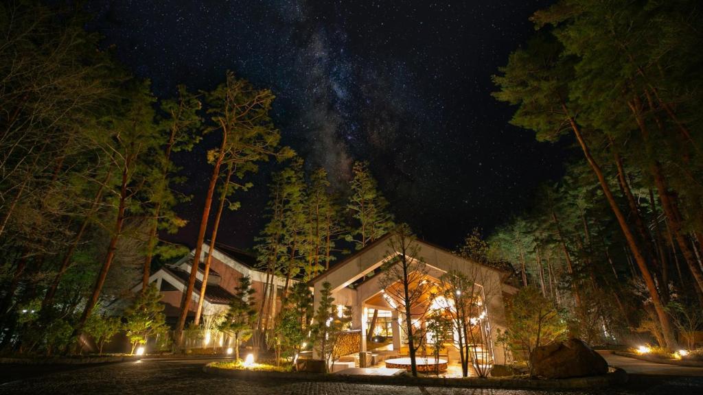 a house in the middle of a forest at night at Kyukamura Retreat-Azumino-Hotel in Azumino
