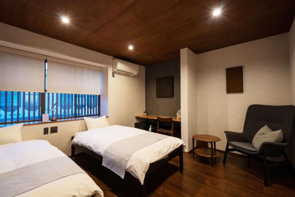 a bedroom with two beds and a chair and a window at ZENYA - Vacation STAY 89346v in Nakano
