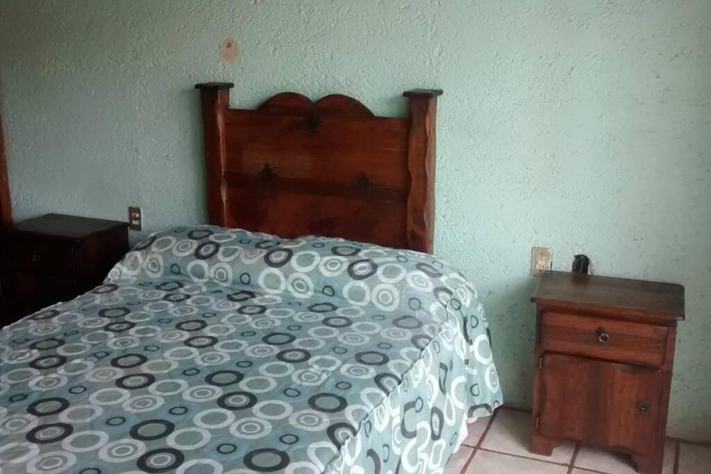 een bed met een zwart-wit dekbed en een nachtkastje bij Habitaciones disponibles en los nogales Pátzcuaro in Pátzcuaro