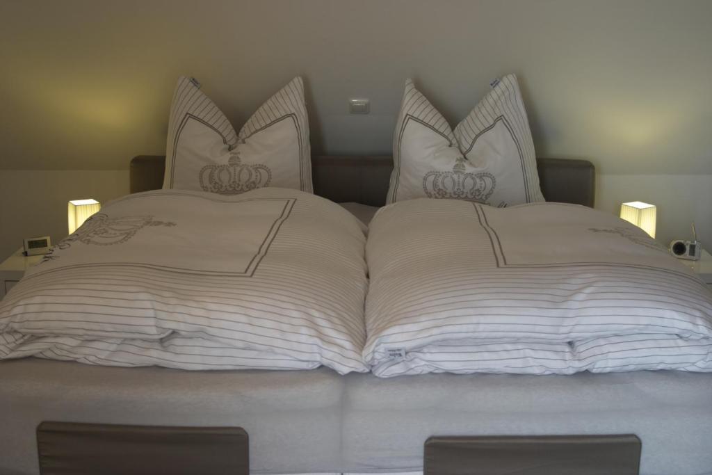 1 cama grande con sábanas y almohadas blancas en Hommage Appartements en Waren