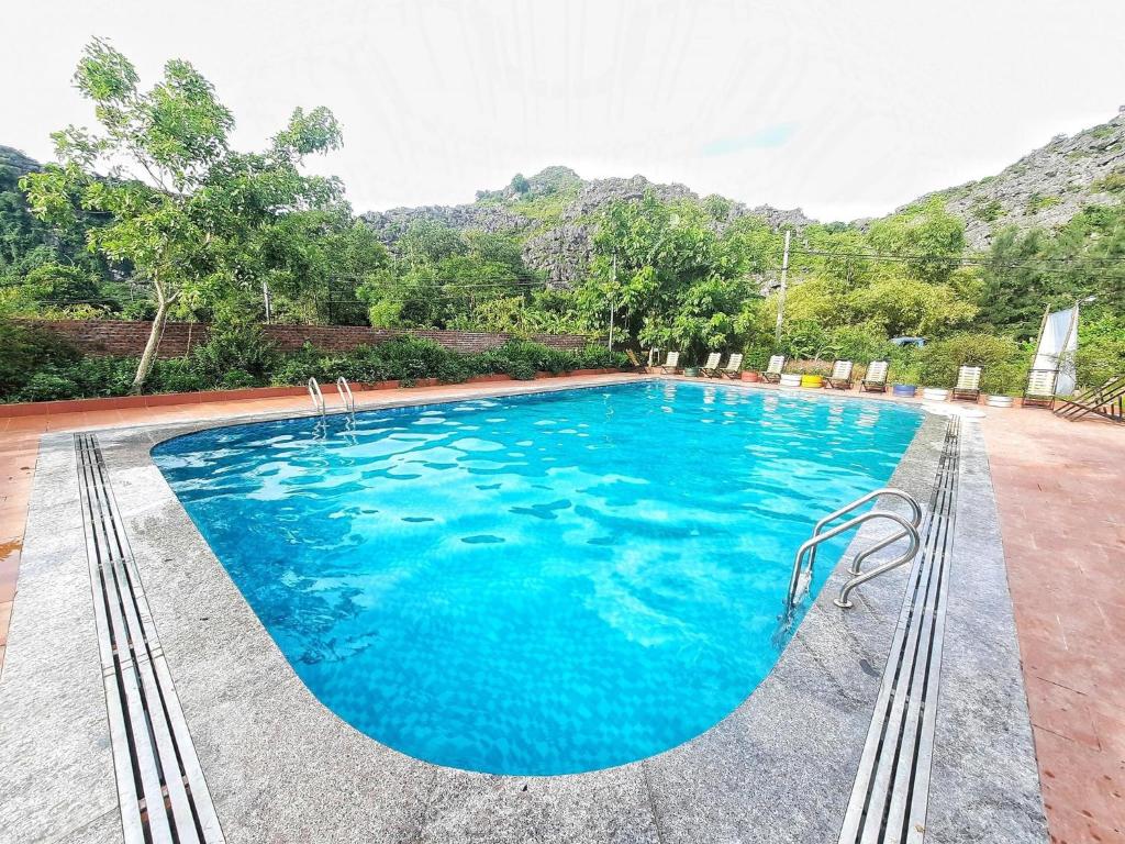 una piscina de agua azul y montañas de fondo en Trang An Resort, en Ninh Binh