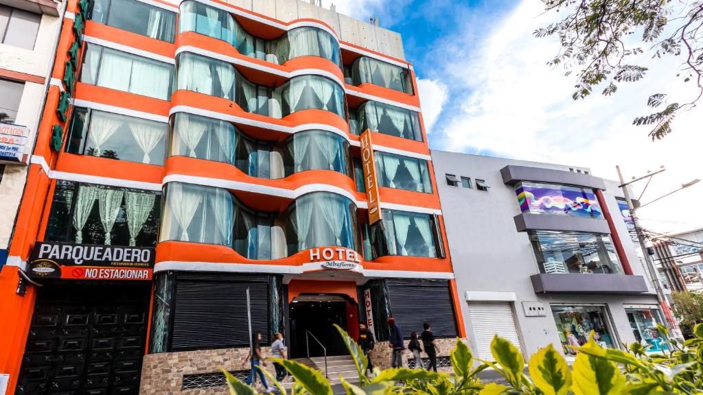 an orange and white building with people in front of it at Hotel Miraflores in Ibarra