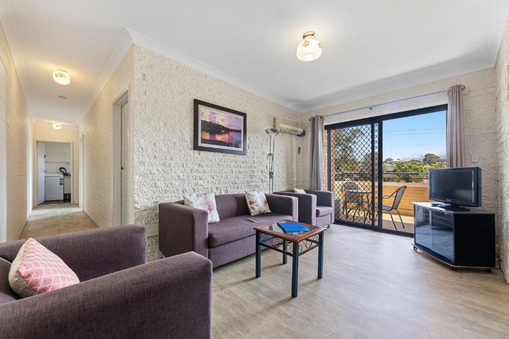 a living room with couches and a tv and a balcony at Apollo Unit 14 1st Floor in Narooma