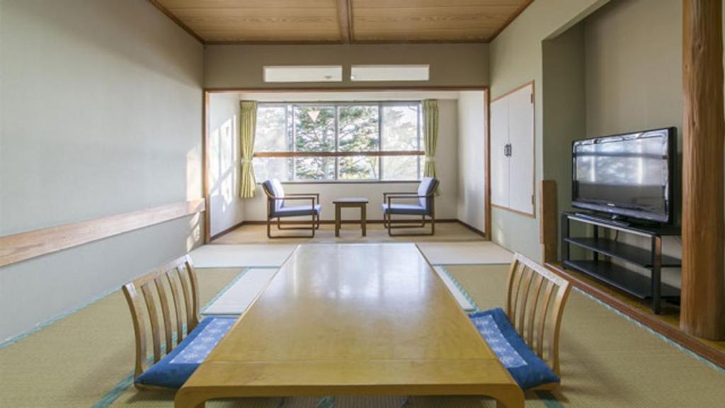 une salle à manger avec une table, des chaises et une télévision dans l'établissement Kyukamura Kesennuma-Ohshima, à Kesennuma