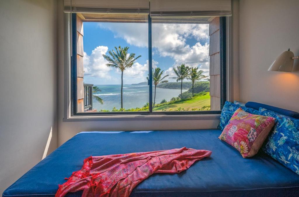 a bed with a large window with a view of the ocean at Sealodge E6 in Princeville