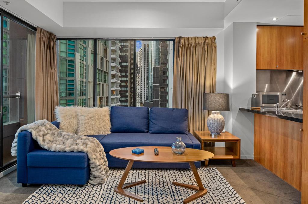 a living room with a blue couch and a table at Exclusive Stays - Gallery Tower in Melbourne