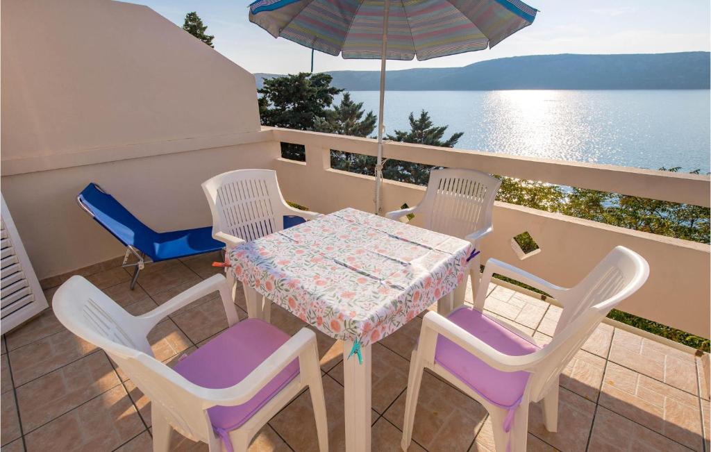 un tavolo con sedie e un ombrellone su un balcone di Lovely Apartment In Stara Novalja With House Sea View a Stara Novalja