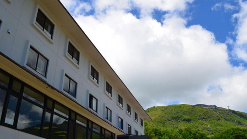 a white building with a hill in the background at Kyukamura Nasu in Nasu