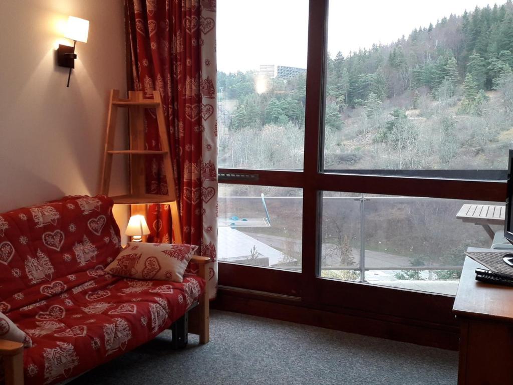 Cette chambre dispose d'un canapé rouge et d'une grande fenêtre. dans l'établissement Studio coquet au pied des pistes - 2/3 pers, balcon - FR-1-689-69, à Villard-de-Lans