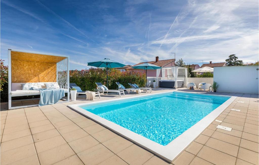 a swimming pool in a backyard with a bed and umbrellas at Lovely Home In Pula With Wifi in Pula