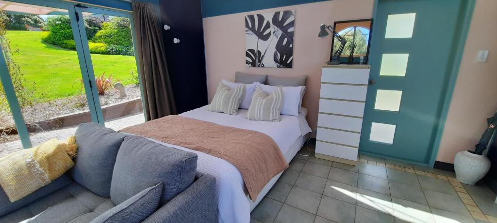 - une chambre avec un lit et un canapé dans l'établissement The Quarters Ocean-View Chalet, à Gisborne