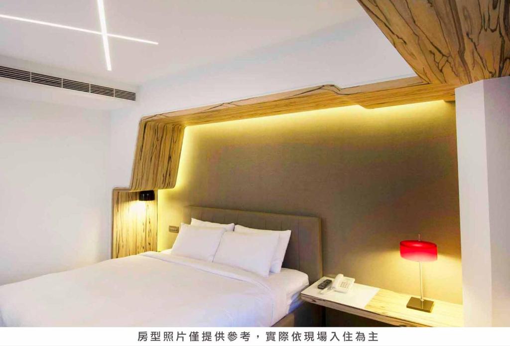 a bedroom with a bed with a lamp and a phone at Royal Hotel Group- Central Park Branch in Kaohsiung