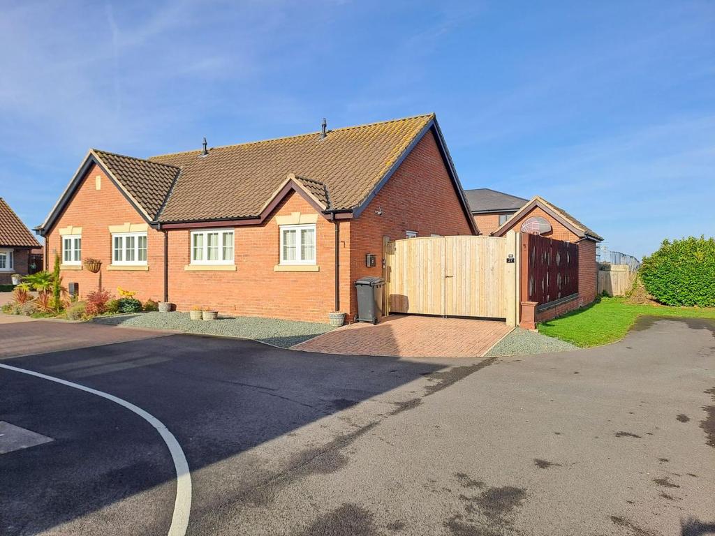 a brick house with a wooden fence on a street at Autumn Lodge in Mablethorpe