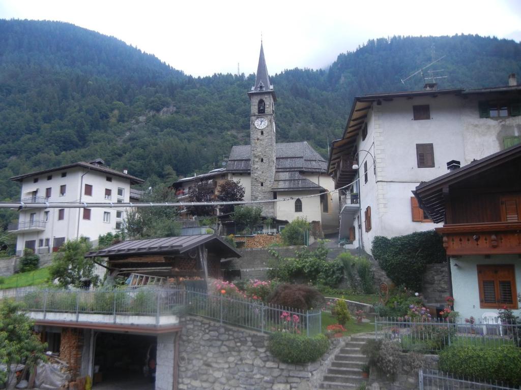 a small town with a clock tower in the mountains at Maso Capitel Appartamento in Commezzadura