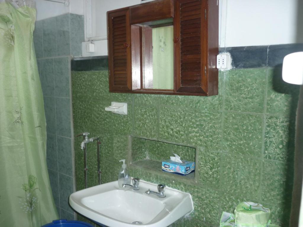 Un baño verde con lavabo y espejo. en Hostal Cotroneo, en Viña del Mar