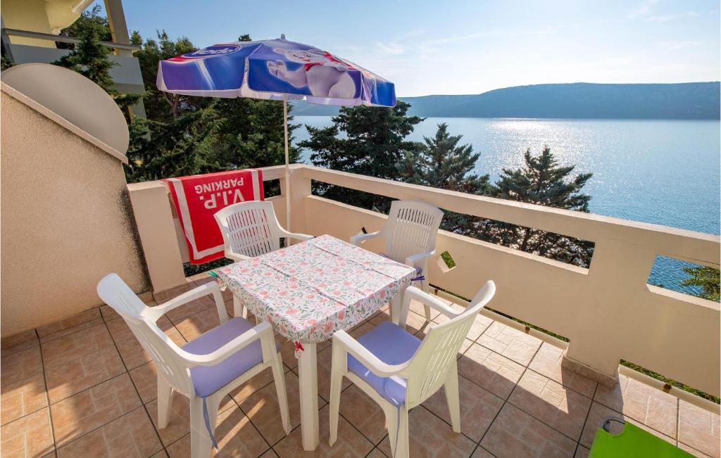 a table and chairs and an umbrella on a balcony at Gorgeous Apartment In Stara Novalja With Kitchenette in Stara Novalja