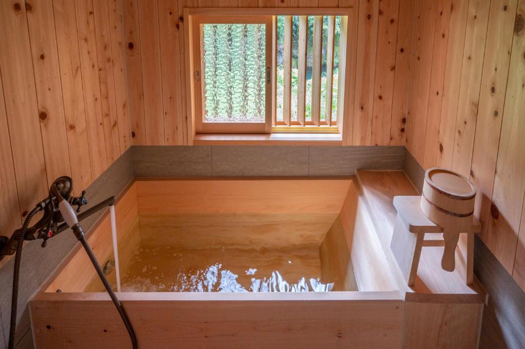 Una bañera en una habitación de madera con agua. en 古民家一棟貸し宿　山のめぐみ舎, en Niyodogawa