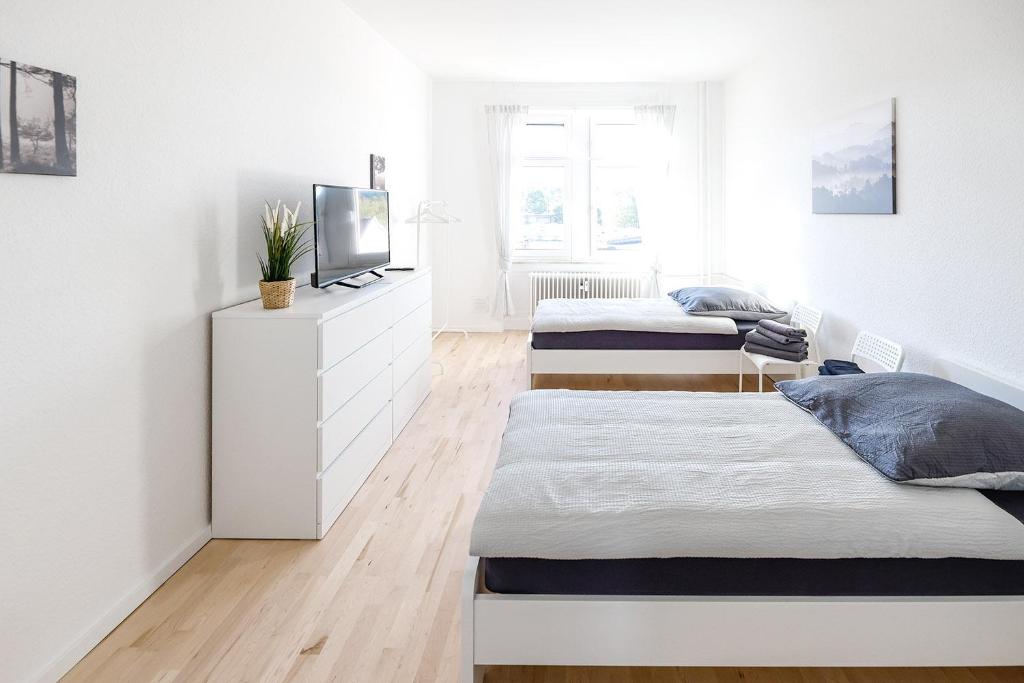 1 dormitorio con 2 camas y un tocador con TV en Modern & Chic Apartment with Balcony, en Gravenbruch