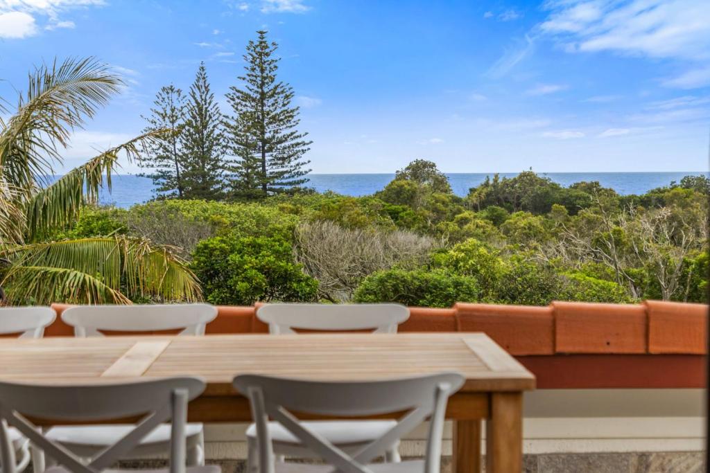 a wooden table and chairs with a view of the ocean at Peregian Beach Apartment in Peregian Beach