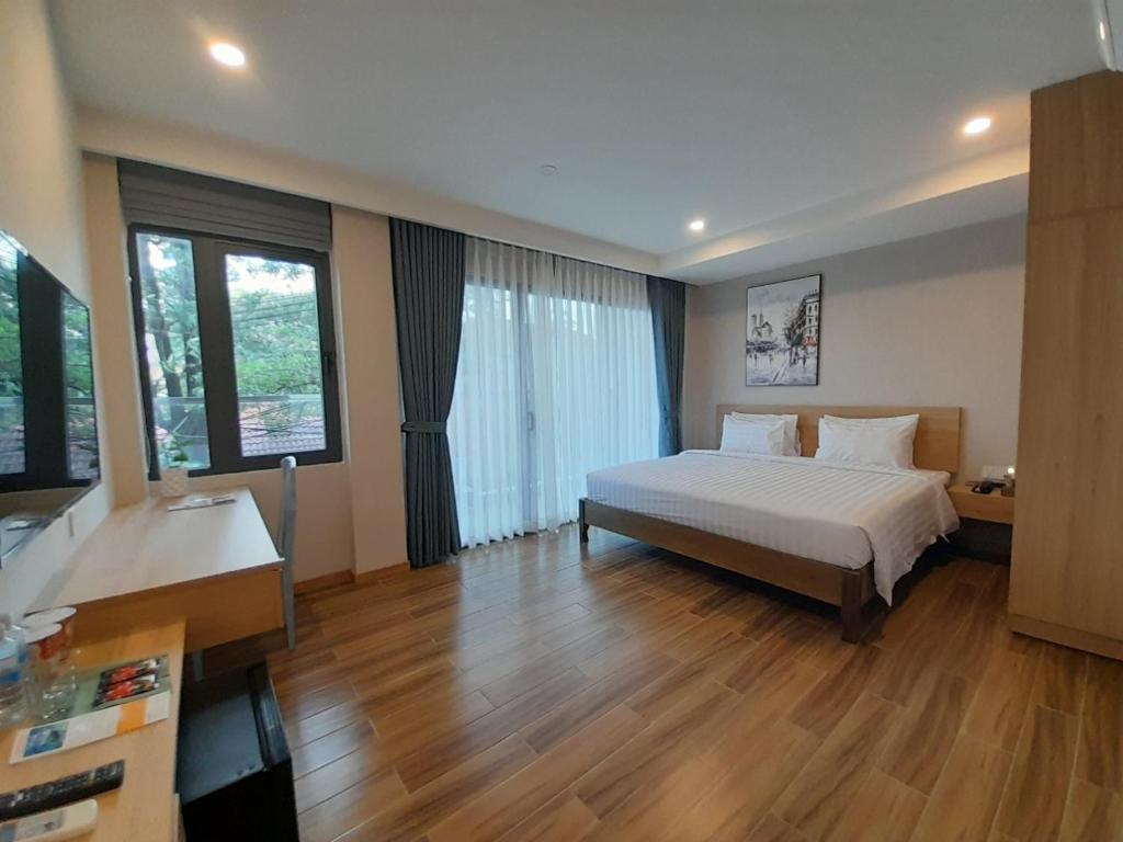 a bedroom with a bed and wooden floors and windows at Happy Home in Nha Trang