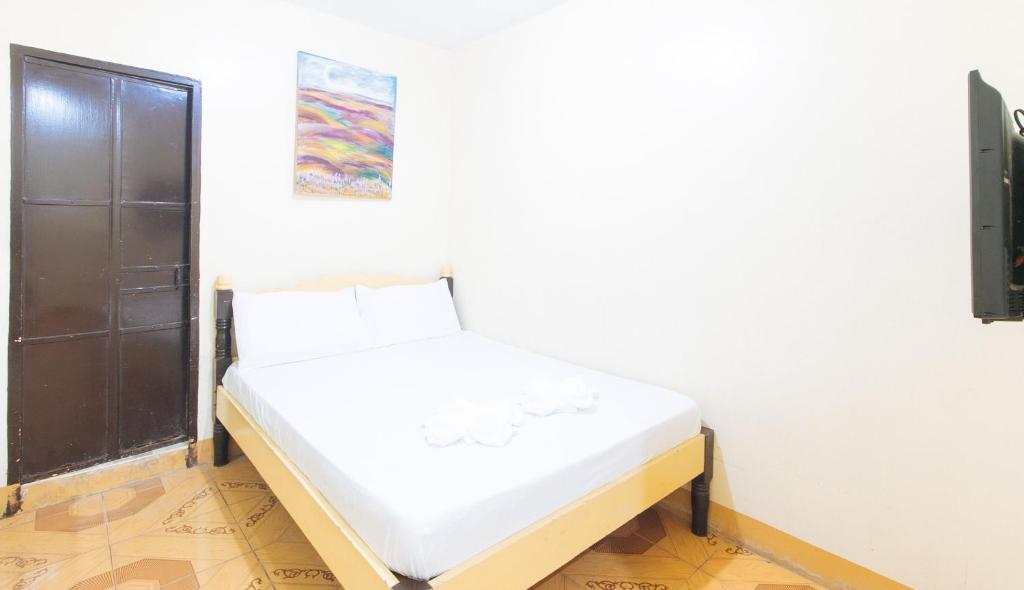 een slaapkamer met een wit bed in een kamer bij Maliwalo Inn Tarlac by RedDoorz in Tarlac