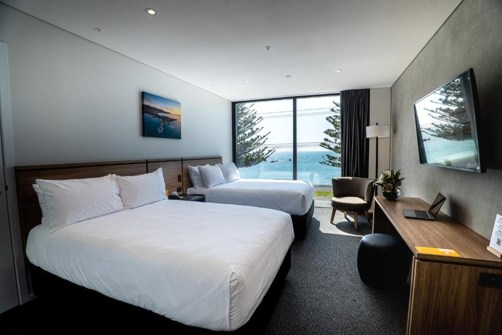 a hotel room with two beds and a desk at Sudima Kaikōura in Kaikoura