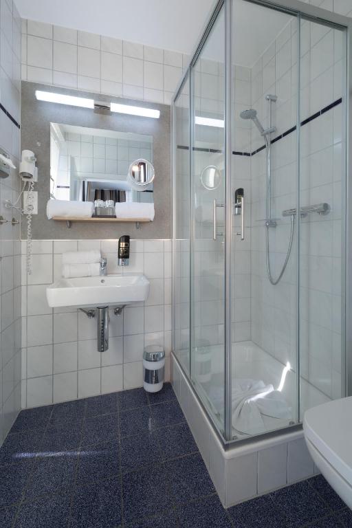 a bathroom with a glass shower and a sink at Hotel Jellentrup in Münster