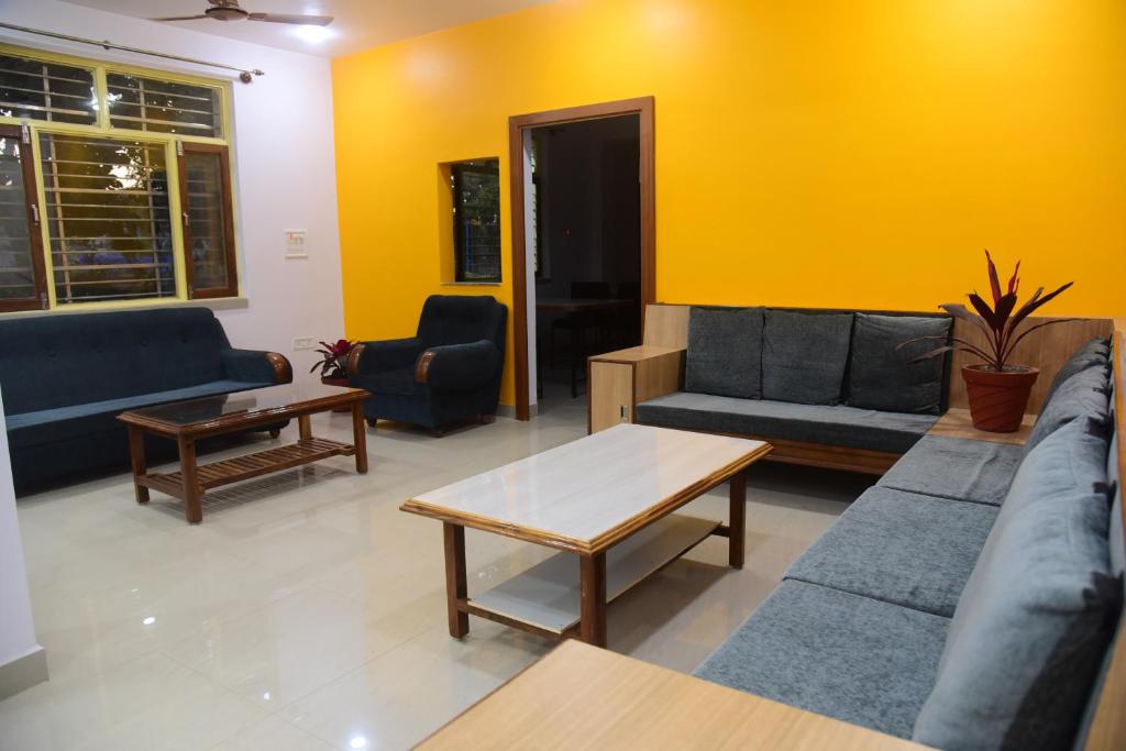 a living room with couches and tables and a yellow wall at Hotel Nikunj in Hazārībāg