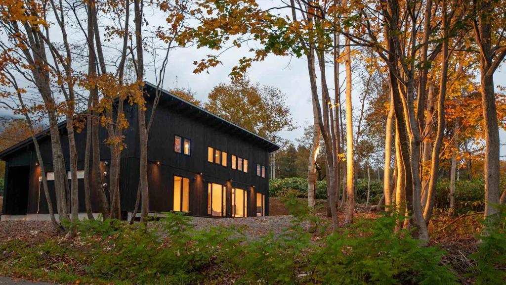 a black house in the middle of a forest at Annupuri Chalets - Niseko in Niseko