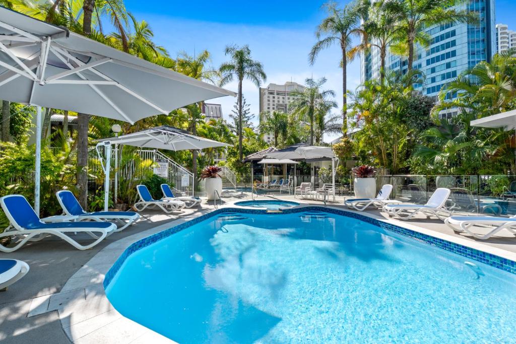 a swimming pool with chairs and umbrellas at a hotel at Coco Bella Retreat in Central Surfers - sleeps 6-8 in Gold Coast
