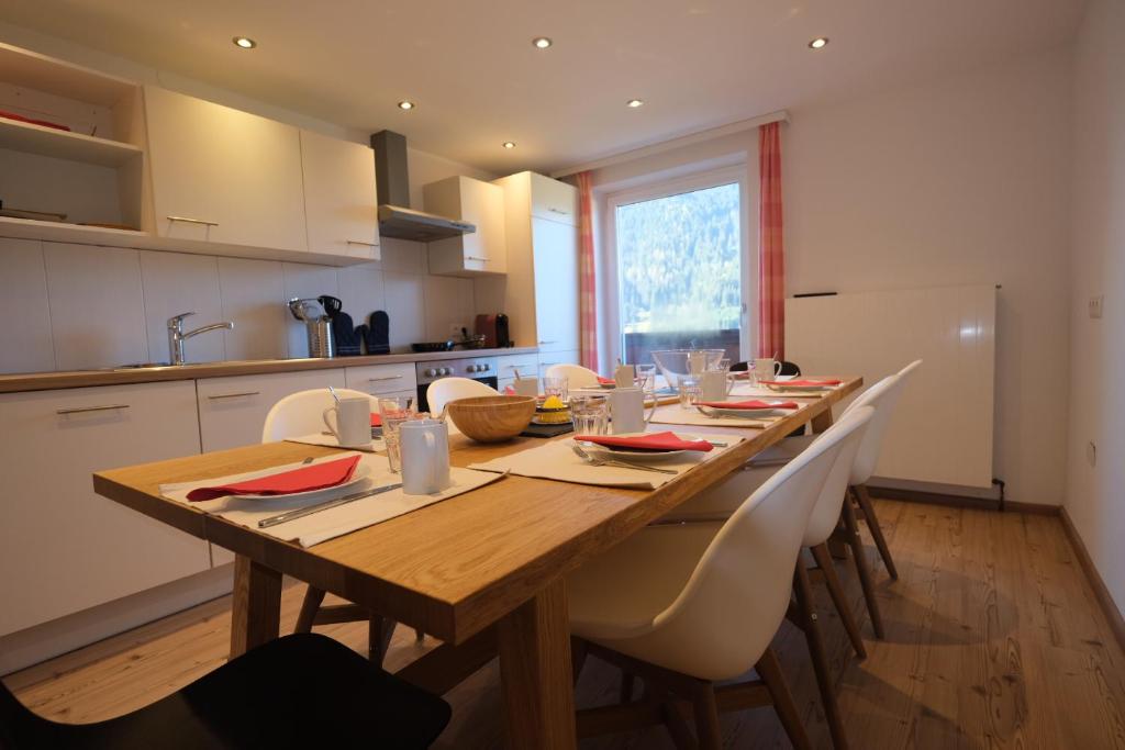 een keuken met een lange houten tafel en witte kasten bij GO FOR MOUNTAINS Appartements in Eben im Pongau