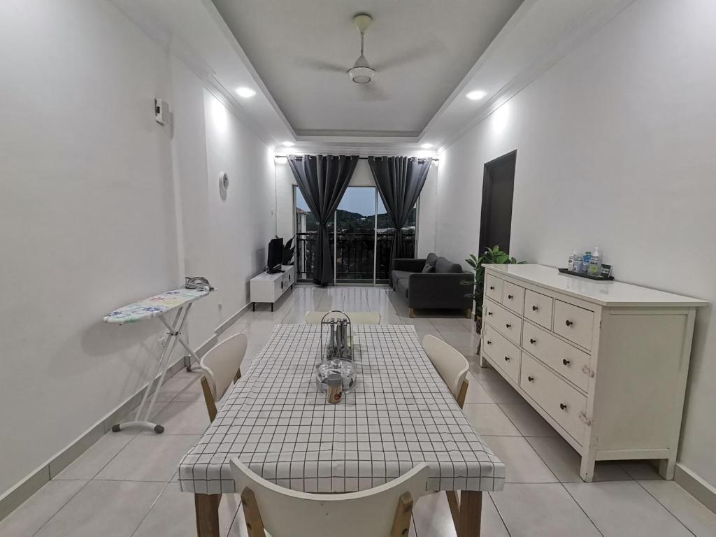 a kitchen with a table and chairs and a living room at Yuslina Homestay in Bandar Puncak Alam