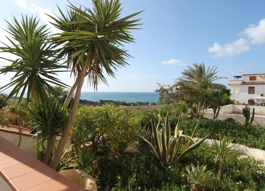 Blick auf einen Garten mit Palmen und das Meer in der Unterkunft La Vecchia Marina sul mare in Marinella di Selinunte