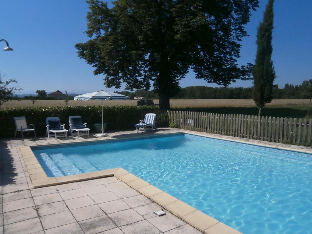 een zwembad met 2 stoelen en een hek bij La Ferme Montplaisir in Montesquieu-Volvestre