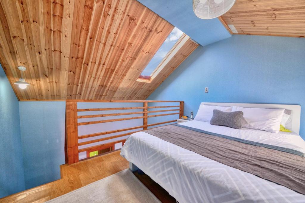 Un dormitorio con una cama con paredes azules y techos de madera. en Yoon and Park Pension en Yangpyeong