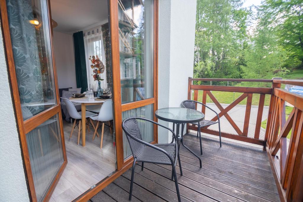 a balcony with a table and chairs on a deck at Apart Invest Żeromskiego 15/8 in Szklarska Poręba