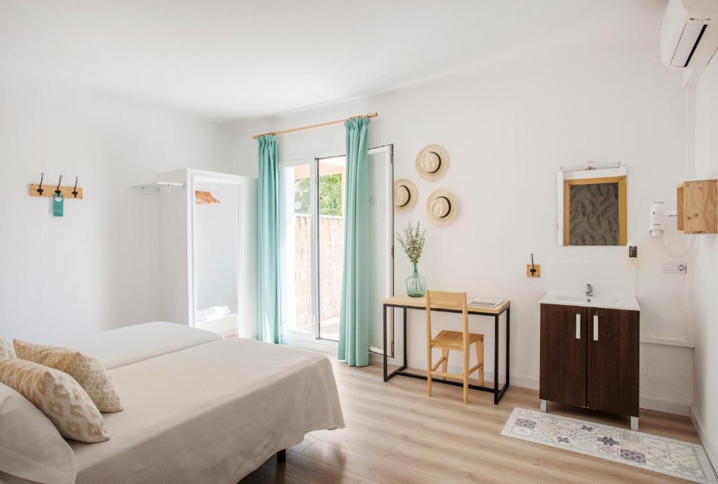 a white bedroom with a bed and a table at Forenna Hostel in El Arenal