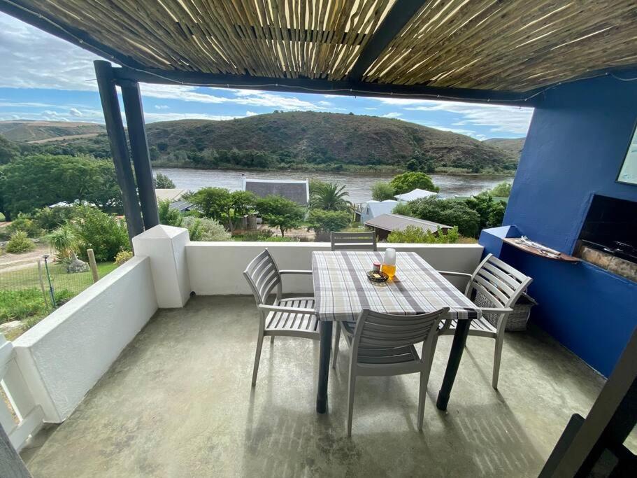 einen Tisch und Stühle auf einem Balkon mit Aussicht in der Unterkunft Riverdance Cottage in Malgas