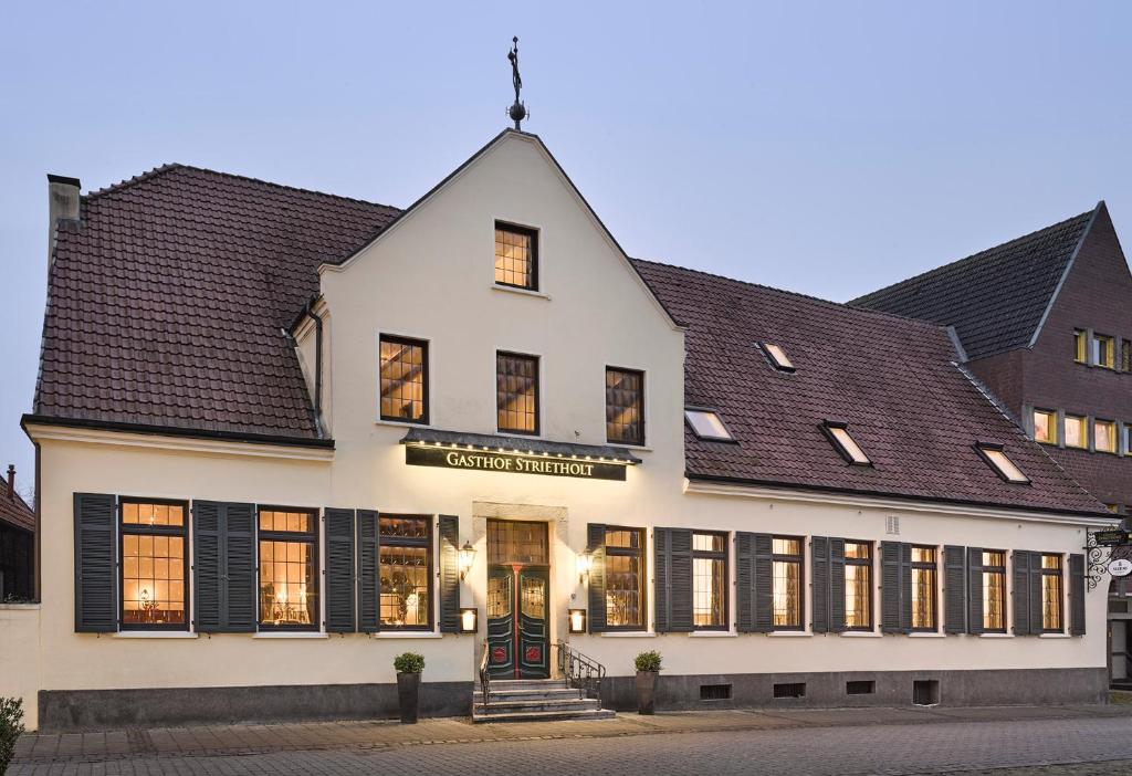 Everswinkel的住宿－Gasthof Strietholt，一座白色的大建筑,设有黑色百叶窗