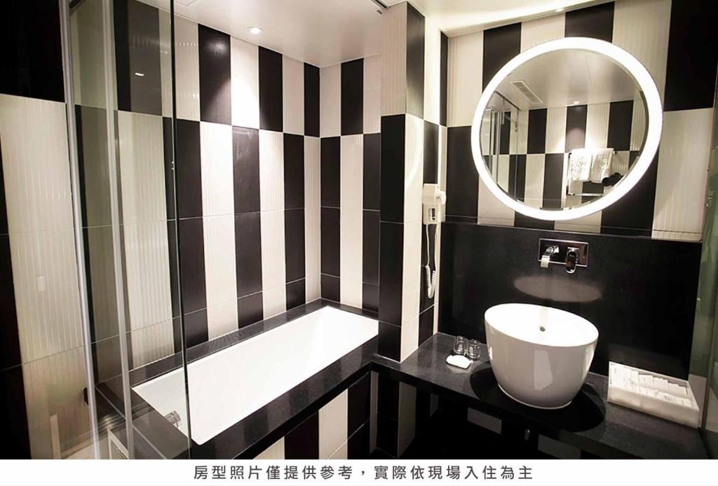 a black and white bathroom with a sink and a mirror at Royal Group Hotel Minghua Branch in Kaohsiung