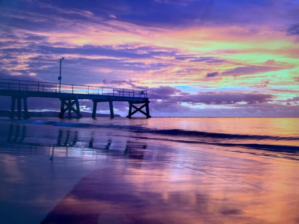 a pier on the beach with a sunset at Jetty Road Granny Flat in Normanville