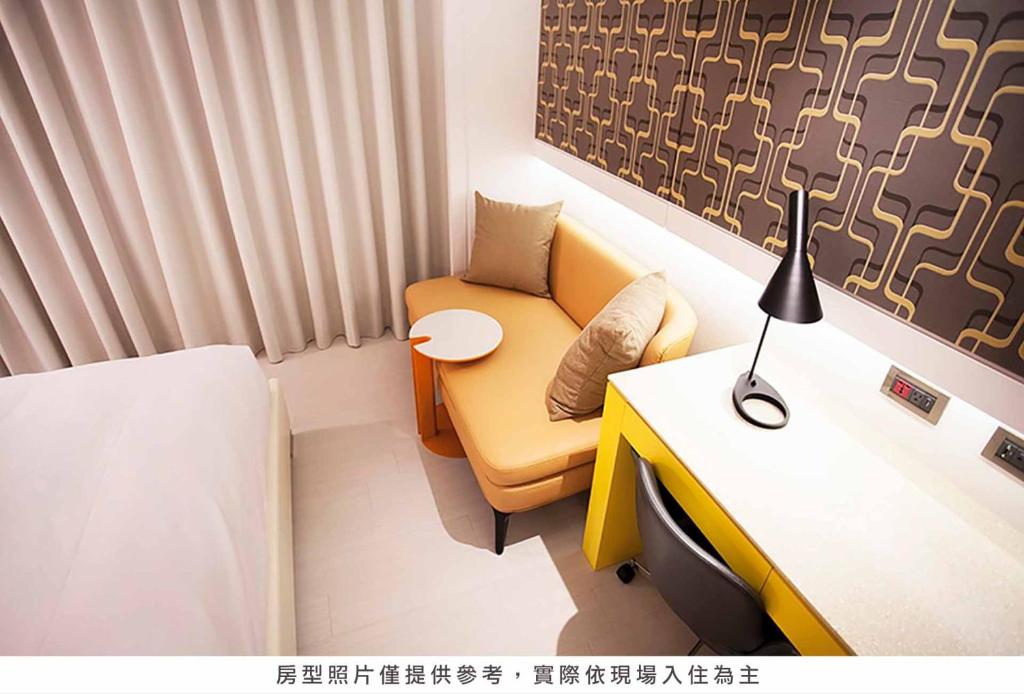 a room with a couch and a table and a desk at Royal Group Hotel Minghua Branch in Kaohsiung