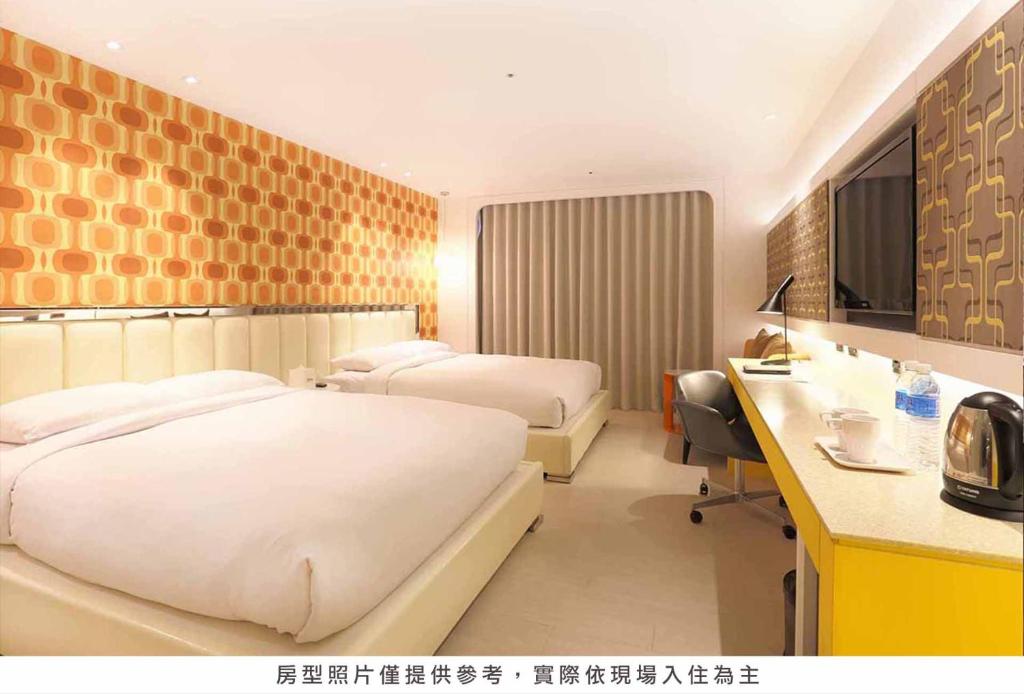 a hotel room with two beds and a desk at Royal Group Hotel Minghua Branch in Kaohsiung