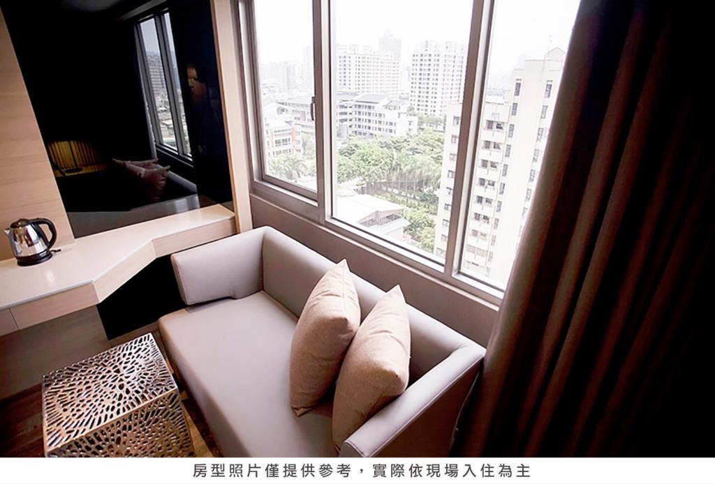 a white couch in a room with a large window at Royal Group Hotel Minghua Branch in Kaohsiung