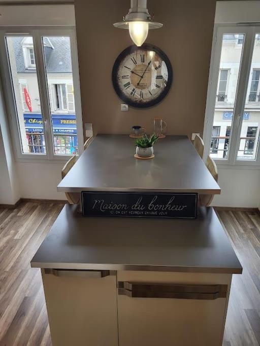 a room with a clock on the wall and a table at Très bel appartement cosy en hyper centre in Romorantin
