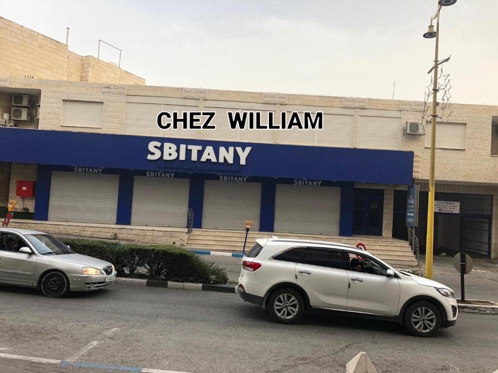 Chez William في بيت لحم: سيارتين متوقفتين في موقف للسيارات امام مبنى
