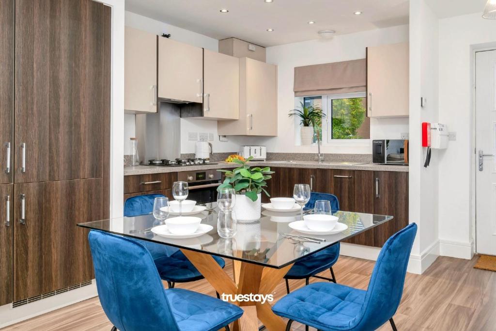 a kitchen and dining room with a table and blue chairs at NEW Berkley House by Truestays - 3 Bedroom House in Stoke-on-Trent in Etruria