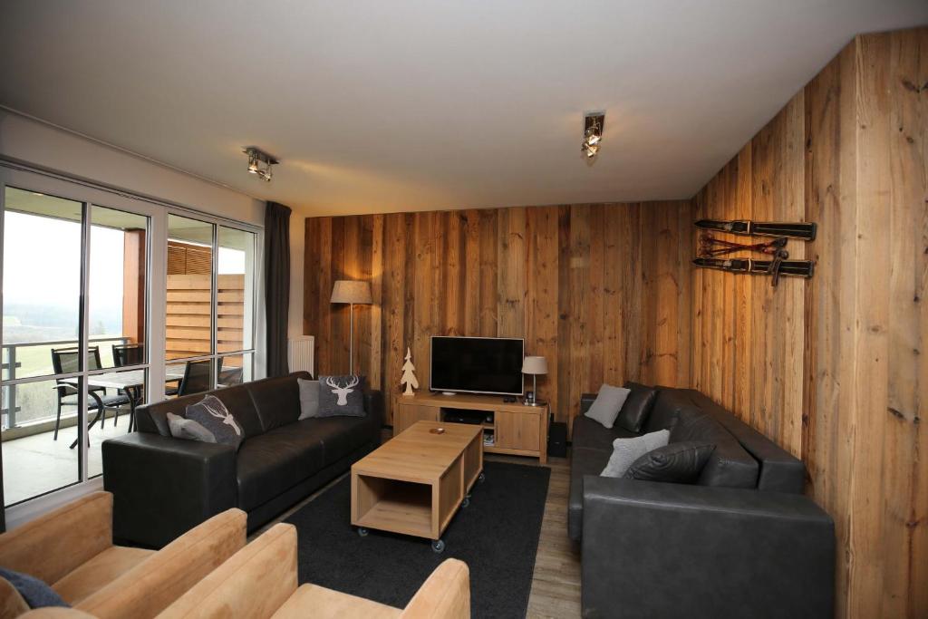 een woonkamer met houten lambrisering en een televisie bij Ferienwohnung Bergwiese in Winterberg