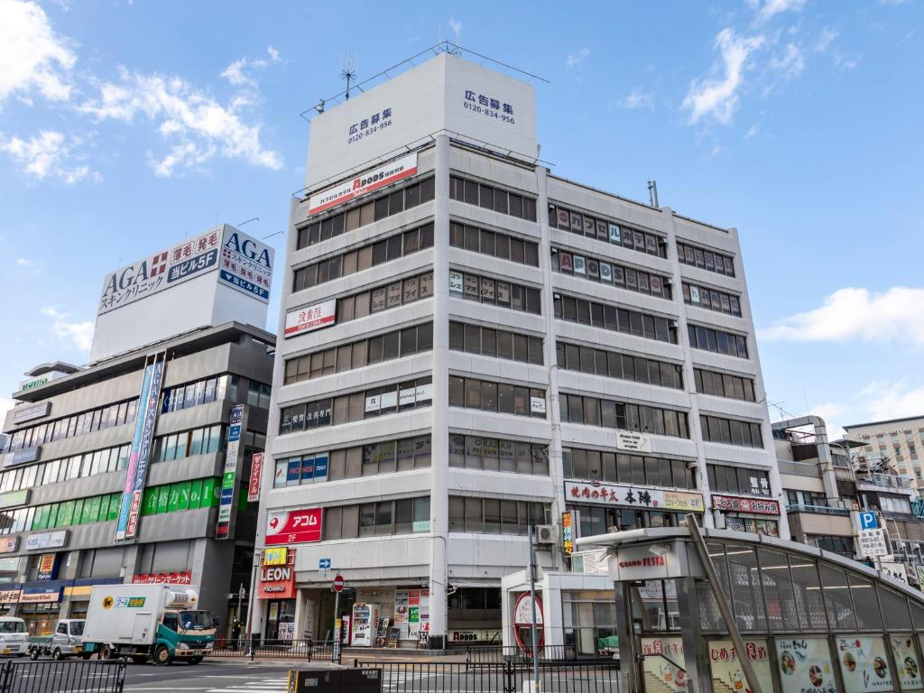 un edificio blanco alto en una calle de la ciudad en Tabist CapsuleHotel APODS Himeji Station en Himeji